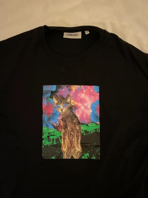 Svart T-shirt med katt - Superkattig (ha-ha!) svart t-shirt med en psykadelisk rave/disco-kisse på! Storlek XS. Köpt på Junkyard för 400kr. Använd fåtal gånger. Från rökfritt och djurfritt hem! 