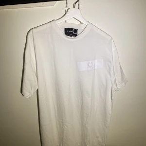 Raf Simons X Fred Perry Tee - Hej, säljer min feta T-shirt från Raf Simons X Fred Perry collaben. Den är i väldigt bra skick och storlek 42, vilket motsvarar Large ungefär. Priset är inte hugget i sten. Hör av dig!