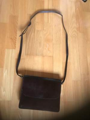 Brun läderväska handväska med många fack. Obetydligt använd, som ny! Reglerbar axelrem. En magnet knäppning framtill och Dragkedje fack baktill. Ett fack inuti. Ren och fräsch och hel. 