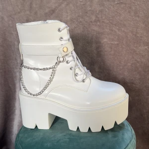 Vita breda klackar  - Ett par vita “Breda”-klackar med kedjor på sidorna, använda en gång till skolavslutning och är i väldigt bra skick, st: 40 men är små i storlek