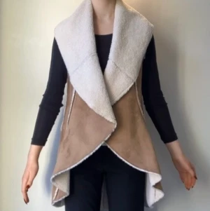 Shearling väst  - Lång shearling väst med fuskpäls och vegansk mockaimitation. Från Saks Fifth Avenue. Använd typ tre gånger.