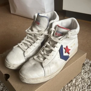 Converse All Star Pro Leather - Ett par vita Skateanpassade Converse skor. Valanvända och kosmetiskt slitna men fortfarande hela och vita. Bra för skejtare på en budget!