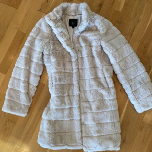 Fuskpälsjacka Dorothy Perkins  - Jättefin, otroligt mjuk och varm kappa/jacka i fuskpäls från Dorothy Perkins. Gräddvit med gräddvitt satinfoder. Använd en gång, som ny. 