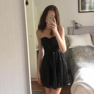 Svart glittrig klänning - Söt strapless klänning med paljetter. ❤️Insyd kupa, passar A-B. Säljer då jag tänkte ha den på nyår men hittade en annan klänning. Aldrig använd. Skriv för fler bilder 💕