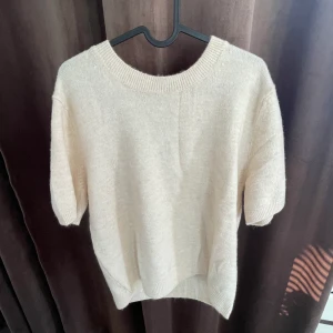 Topp från Hm - Superfin och jätteskön stickad t-shirt från Hm, som ny! Säljer endast för att jag hellre ville köpa en annan storlek istället🥰Materialet är lent och består av 52% polyester, färgen skulle jag säga är benvit/ ljusare beige:) Köparen står för frakt, 66kr
