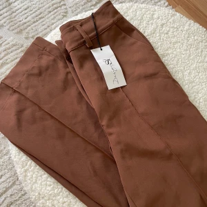 Byxor DesignBySi  - Ursnygga kostymbyxor från DesignBySi i den perfekta bruna färgen. Säljer då de tyvärr är lite stora.  Storlek XXS, helt oanvända med prislapp kvar