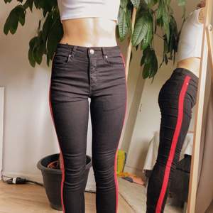 Svarta tajta jeans med rött streck, knäppe istället för dragkedja. Bra fickor både fram och bak! 