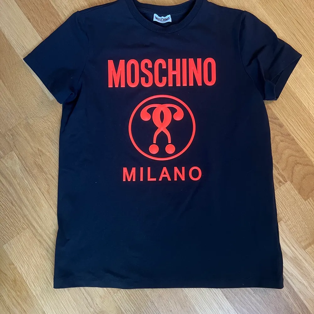 En oanvänd svart Moschino Milano T-shirt i storlek 14 (ungdoms storlek) men passar precis som S. Köparen betalar frakten. . T-shirts.