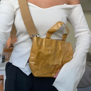 Handväska WEEKDAY - Senapsgul handväska från Weekday med ett skrynkligt uttryck. Jättefint skick! Avtagbart Axelband. Dragkedja i väskan. Fraktkostnad 49kr.