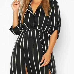 Randig skjortklänning  - En svart och vitrandiga skjortklänning i knähöjd med tunt och svalkande material. Väldigt lång så är du kort kommer den nå dig till fotknölarna! Aldrig använd. 