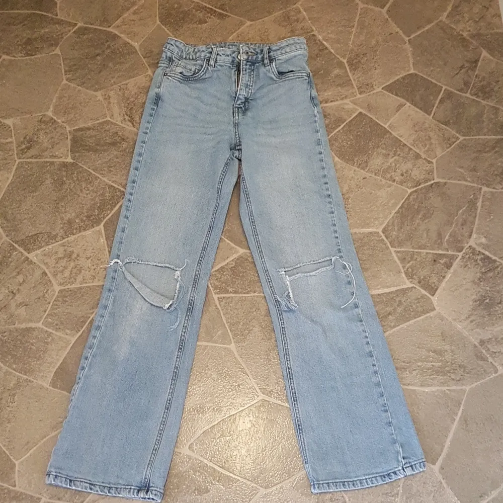 Ett par blå jeans från H&M som är slätt och har hål.. Jeans & Byxor.