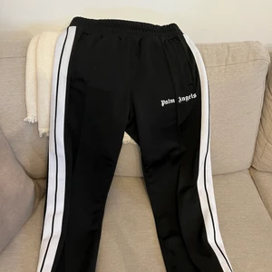 Palm Angels Track Pants Black/White - Palm Angels byxor  Storlek: Medium Färg: Svart & Vit Skick: 8/10 (Inga hål, skador på tryck eller liknande) Nypris: 3700kr (kan variera) Pris: 2250kr  (Kvitto från Farfetch finns)  SÄLJES I BEFINTLIGT SKICK!