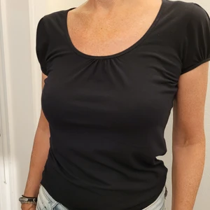 Svart Topp - Snygg enkel Svart Topp stl.S Kort lite puffig ärm, urringning med litet rynk. Tightare , insvängd modell. Bomull. Använd, välhållen. Älskar denna modell, men den har tyvärr blivit för tight för mig. Frakt tillkommer.