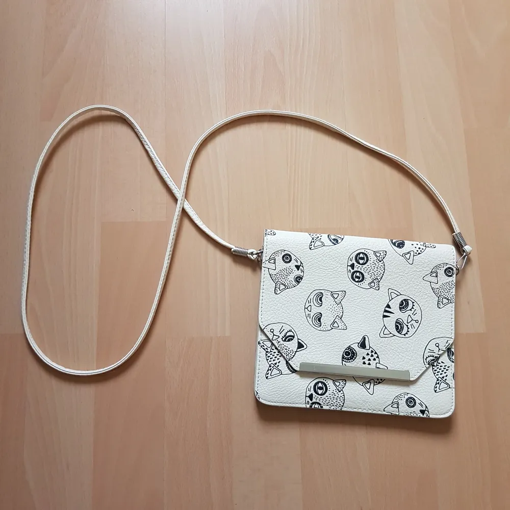 Jättesöt axelbandsväska i en off-white läderimitation, med katter på. Är inte helt säker på vart den är ifrån, men troligtvis Monki. Den är ca 17x19 cm, och har 3 fack.. Accessoarer.