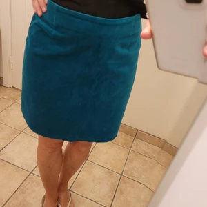 Kort kjol sammet - Superfin kort kjol i grönblå mjuk sammet, stretchig. Stl.38 M. Fin Dragkedja guld bak.Sitter fint i midjan men kan också bäras på höften. Använd en gång, så gott som ny. Finns ej kvar i butik. Då den tyvärr ej kommer till användning, så kollar intresse.