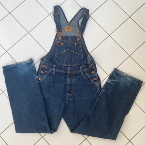 Hängselbyxor  - Ett par mörkblå hängselbyxor, som sitter lite baggy på s/xs.