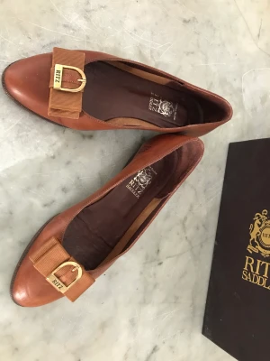 Ritz skor vintage - Ritz skor i brunt läder i storlek 37 ( ja- det står 36,5 i sulan. Men det här är definitivt en sko som passar en 37 fot. ) Jag har själv 37,5 och min fot är bekväm i skon. Skon har väll levt och dansat runt på stan med någon som töjt den lite. Men den är 