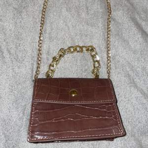 Säljer min mini väska. Den är i färgen brun med guldiga detaljer. Jätte gullig väska som passar bra till nästan alla outfits.