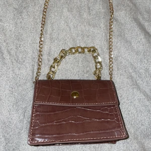 Mini bag - Säljer min mini väska. Den är i färgen brun med guldiga detaljer. Jätte gullig väska som passar bra till nästan alla outfits.