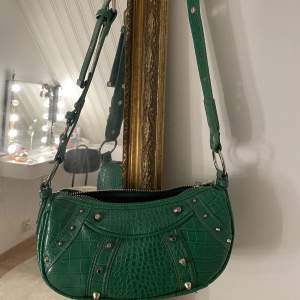Säljer denna mörkgröna axelremsväskan med nitar på, den är i ett bra skick då den inte har användts så mycket😊 Går att göra bandet längre eller kortare.