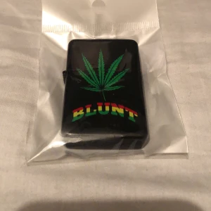 Zippotändare - Tändare där det står Blunt med en cannabis planta. Fyllbar om man lyfter silver tändaren.
