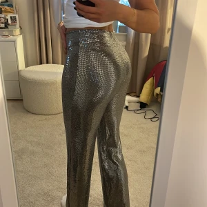 Lång Glitter/Silver byxa strl S - Ett par långa silverglittriga byxor från Nelly i strl S. Använda en nyår, perfekta till fest. Jag är 178cm lång. ✨