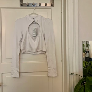Vit croptop🤍 - Vit croptop med öppning på bröstet. Från NAKD, storlek M. Liten fläck på ena armen, kan skicka bild om så önskas. Ny med lappar. Kan mötas i Göteborg eller skicka, köparen står för frakt.