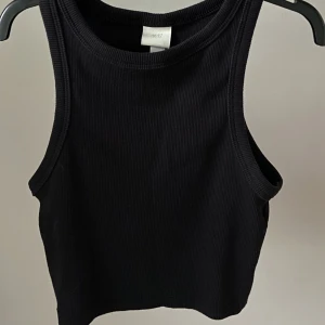 Svart H&M topp - En svart topp ifrån H&M som bara används få gånger. Ganska kort, går ungefär ner under naveln.