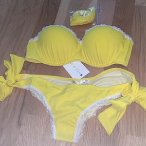 Bikiniset- LOVE BY LOLA - Bikiniset från märket LOVE BY LOLA i färgen gul. Nyskick. Bikiniunderdel är i storleken M. Bikiniöverdelen i storlek S/M. Brazilian, spets och finns band till överdelen. Inköpspris 800kr. Skriv vid frågor och fler bilder.