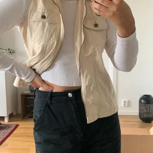 Beige jeansväst  - Beige jeansväst köpt second hand. Fungerande dragkedja som ger västen en mer figursydd look när den är stängd. Två bröstfickor. Fint skick. Är normalt en M/38 men den passar xs-L beroende på önskad passform. 