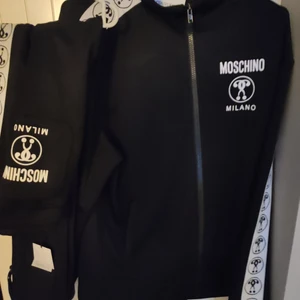 Moschino milano - Helt ny tracksuit av märket Moschino Milano. Strl 48. medium. Använd tracksuit av märker Moschino Milano. Använd endast en gång. Prislappar finns kvar. Köpt på Johnells. Först till kvarn.