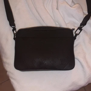Lui Vuitton black Messenger bag  - En svart Lui Vuitton Messenger bag. Den är i bra skick köpt för cirka 2 månader sen. En riktigt fin väska för män som matchar till allt eftersom den är svart 