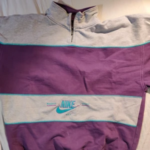 NIKE VINTAGE 1/4  ZIP-lila o grå randig - Vintage Nike quarter zip med pösig och skön passform. Lila och grå randig, med ljus blå stygn. Ljus blått Nike märke i nedre randen. 