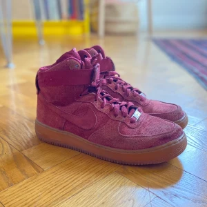 Nike Air force i röd mocka - En specialutgåva av Nike med air force i röd mocka. Inköpta 2017 för 2000kr men använda sparsamt. Inte i nyskick men ändå fina. Innersulan utbytt mot en annan från ett par löparskor för ökad komfort. 