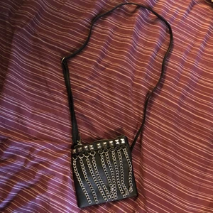 Axelbandsväska - Liten svart axelbandsväska i fakeskinn med nitar och kedjor. Ett litet fack på insidan för mindre grejer. Supercool!!