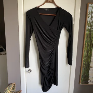 Svart klänning från nelly - Tajt omlottklänning - skönt matrial för sommaren 
