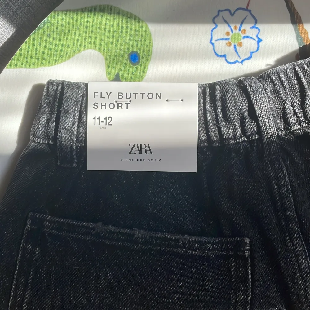 Zara jeansshorts i barnstorlek 11-12 år / 152cm. Oanvända i fint skick. Fyra knappar varav tre tryckknappar och en patentknapp. Justerbara i midjan.. Shorts.