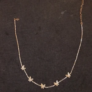 Ett jättefint guld halsband med glimriga silver pärlor, där figuren är fjärilar! Köptes för två veckor sedan och användes bara en gång. - Passar bra med flera assecoarer