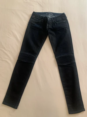 Robin’s Jean jeans med förstärkta knän - Mörkblå/ svarta jeans från Robin’s Jean i storlek 26. Det går bra att skicka eller träffas i Stockholm city. Jeansen är åtsittande längs hela benen. De har förstärkning över knäna och är super sköna. Men för små för mig tyvärr. De kommer från LA i USA.