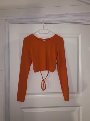 Orange crop top med öppen rygg  - Tröjan är i storlek M Med öppen rygg Den är använd fåtal gånger