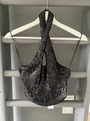 Glittrig festtopp  - Cool glittrig festtopp från Gina Tricot. Korsande band i halsen och öppen rygg. Aldrig använd, storlek S.