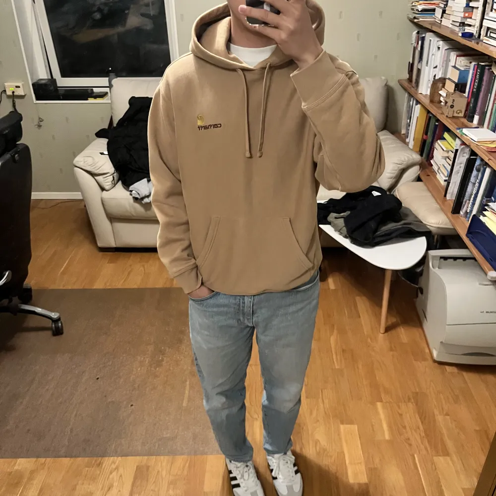 Beige/brun Carhartt hoodie mjuk och skön i nytt skick. Tjock Baggy hoodie som passar perfekt på mig som är brukar bära S-M. Passar perfekt för hösten/vintern. . Hoodies.