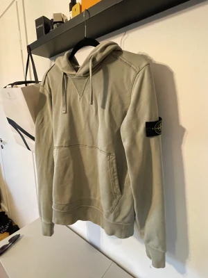 Stone island hoodie - Säljer nu en riktigt snygg stone island hoodie i ljusgrön färg.  Skick 8/10 endast liten slitning vid armen.