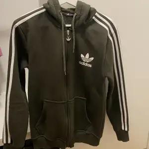 Adidas hoodietröja med dragkedja, khaki. Bra skick och väldigt bekväm. Säljer även matchande underdel (mjukisbyxor)