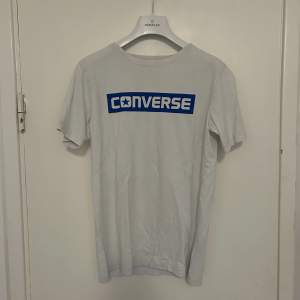 Vit t-shirt med blått converse tryck. Sparsamt använd. Perfekt passform.