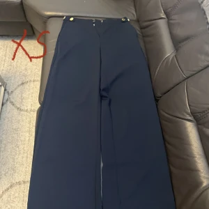 Kostymbyxor - Mörkblå vida kostymbyxor med guldiga knappar. Fint skick strl xs. Går även att mötas i malmö, 200kr