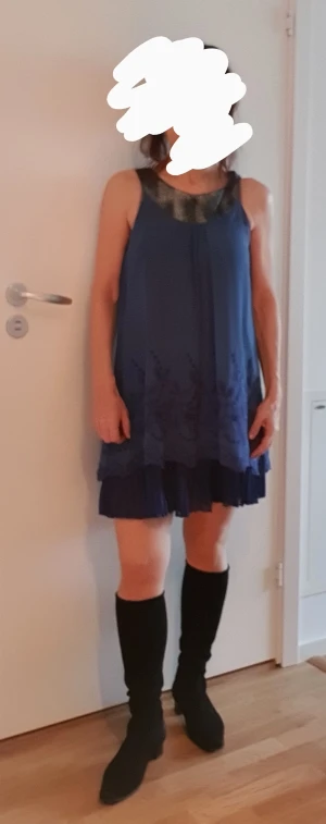 Festklänning  - Blå chiffonklänning med plisserad underkjol. Mycket bra skick. Fina detaljer vid underkanten. Knälång vid kroppslängd 1,60. Har används en gång. Funkar även med vita smala jeans under. Djur-och rökfritt hem.