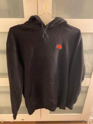 Svart hoodie från h&m med en detalj av en ros, frakt ingår i priset