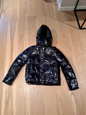 Calvin Klein jacka - Supersnygg jacka inför vintern. Varm puffer med luva i svart glansigt material. Nypris: 2195:- 