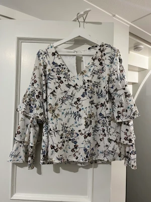 Snygg mönstrad vit blus från Project Unknown  - Häftig blus som har volangiga ärmar som ger blusen dess starka karaktär. Den har en luftig passform och den är normal i storleken. Den har använts ett flertal gånger och är i mycket bra skick. 